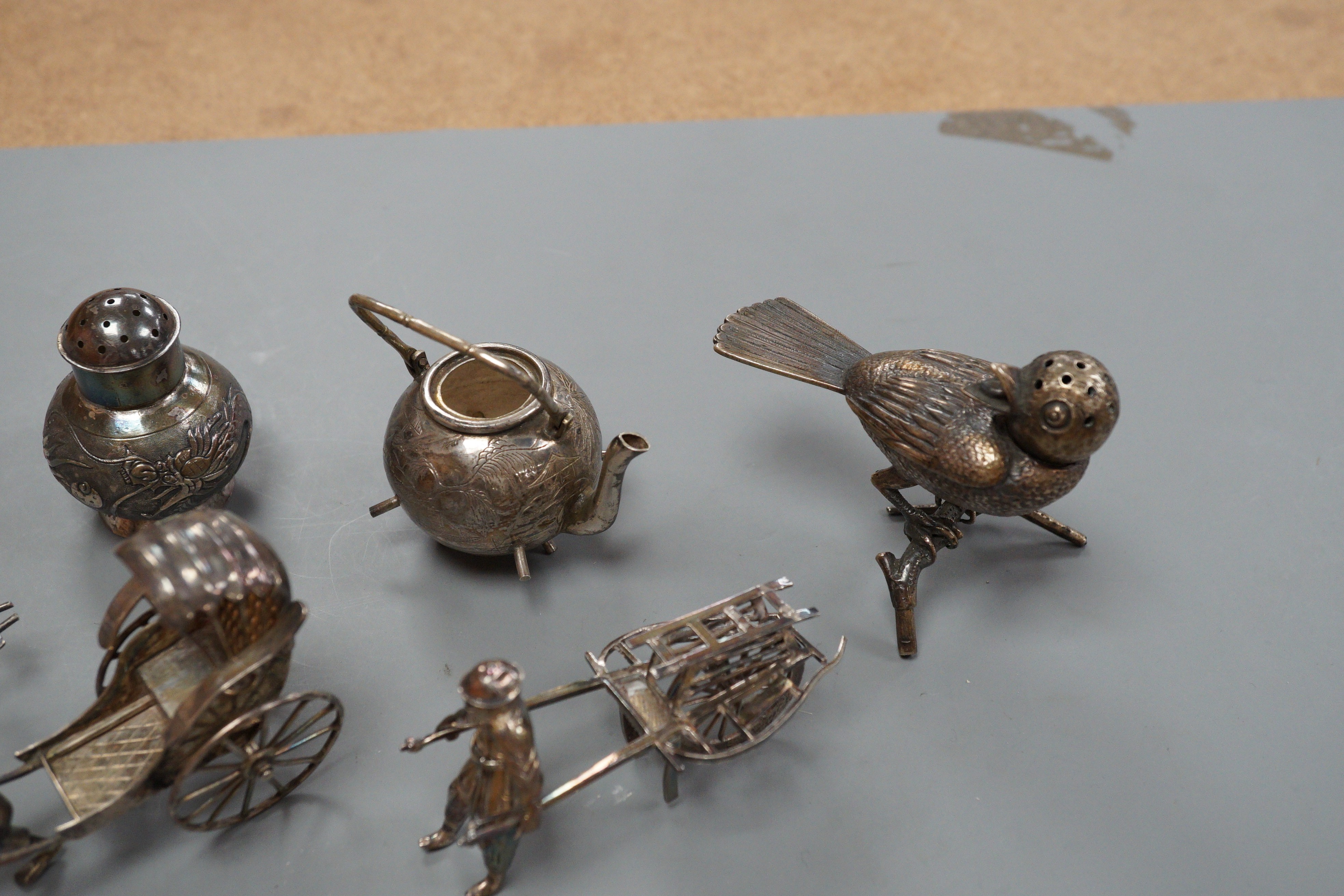 Six assorted miniature white metal items including a Chinese tea kettle on stand (lacking lid), height 93mm, maker CS, a similar rickshaw with driver, maker CH, a Chinese condiment and three other items.